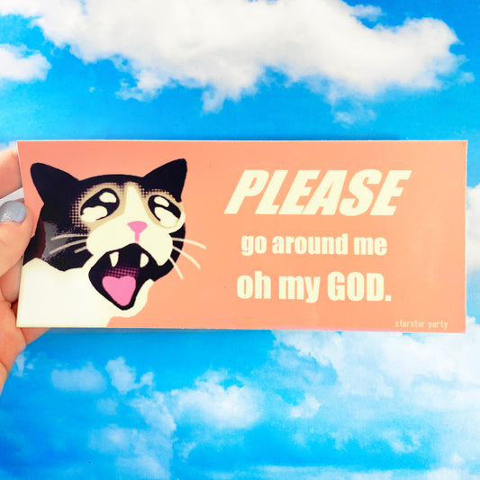 A hand holds a bumper sticker in front of a sky print background. The bumper sticker features a distressed but cute looking cartoon cat on a peach background. The text next to the cat says, "Please go around me, oh  my god".